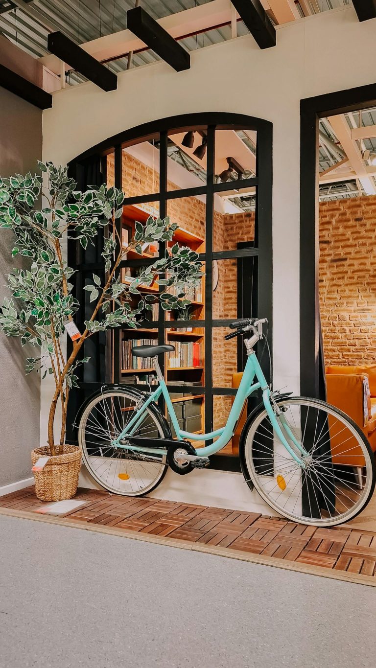 A vintage bicycle placed indoors next to a large window in sunny İstanbul, Türkiye.